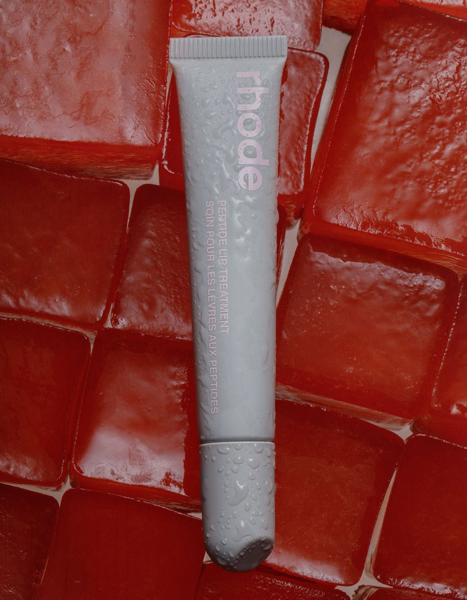 Tube of 'rhode' skincare product on a red textured background